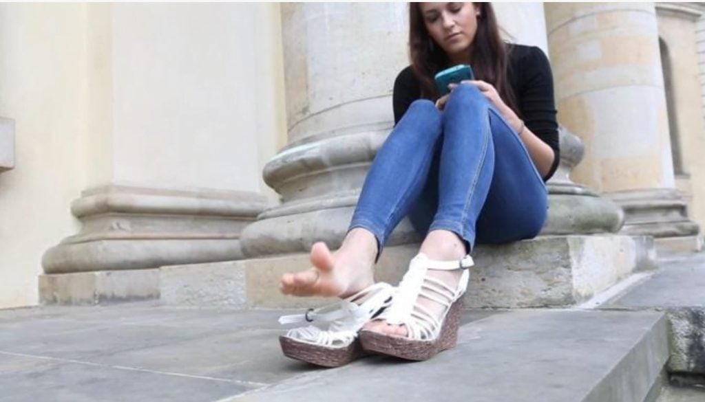 Close-up of beautiful feet of European young woman in wedge-heeled high-heeled sandals